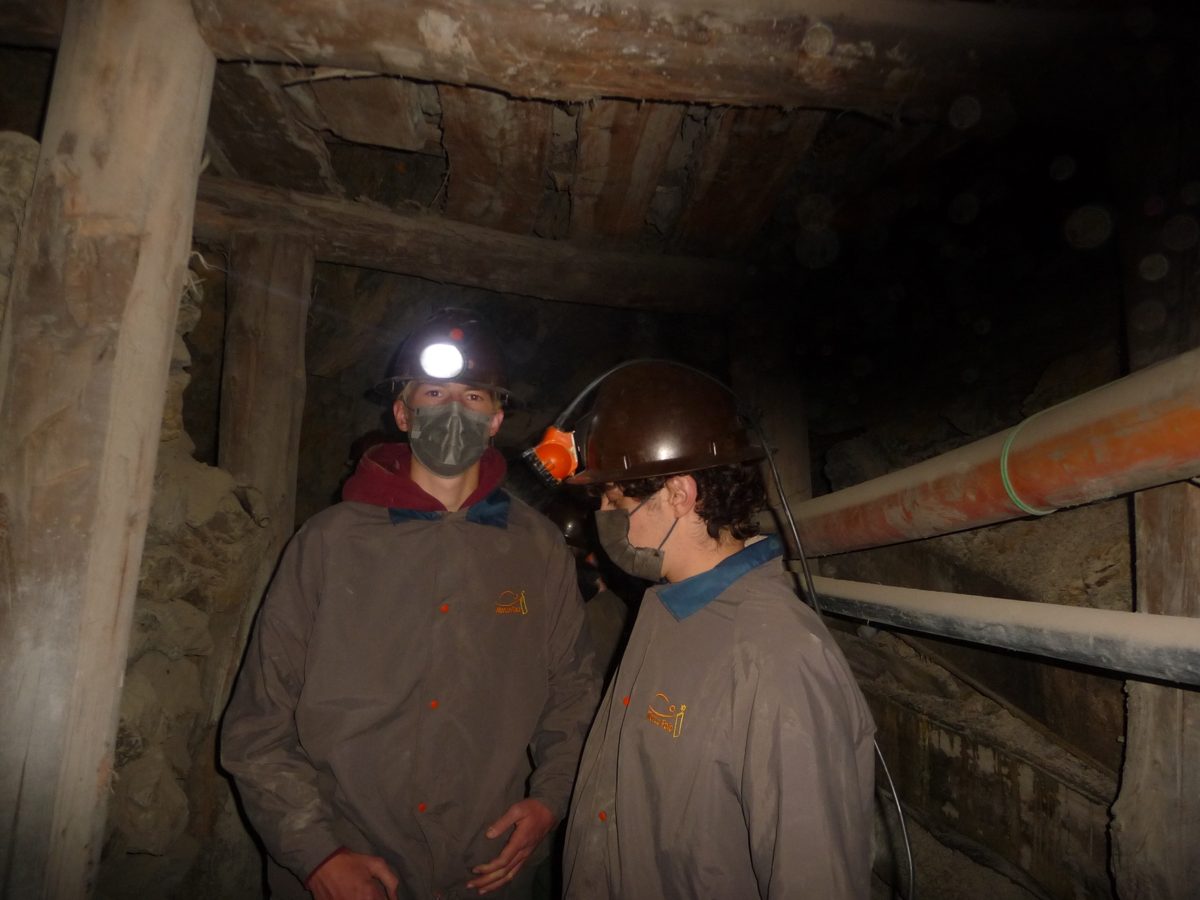 Zwei Austauschschüler mit Helm und Stirnlampe in einem Stollen in Potosí