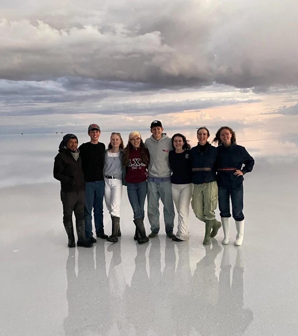 Austauschgruppe steht im spiegelnden Wasser des Salar de Uyuni