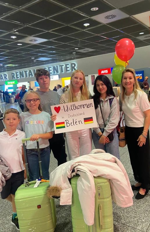 Gastfamilie empfängt ihre Austauschschülerin mit Luftballons und Willkommensschild